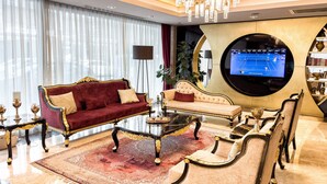 A luxurious living room with a red sofa, a black coffee table, and a round TV screen. - The Conforium Hotel (Istanbul)