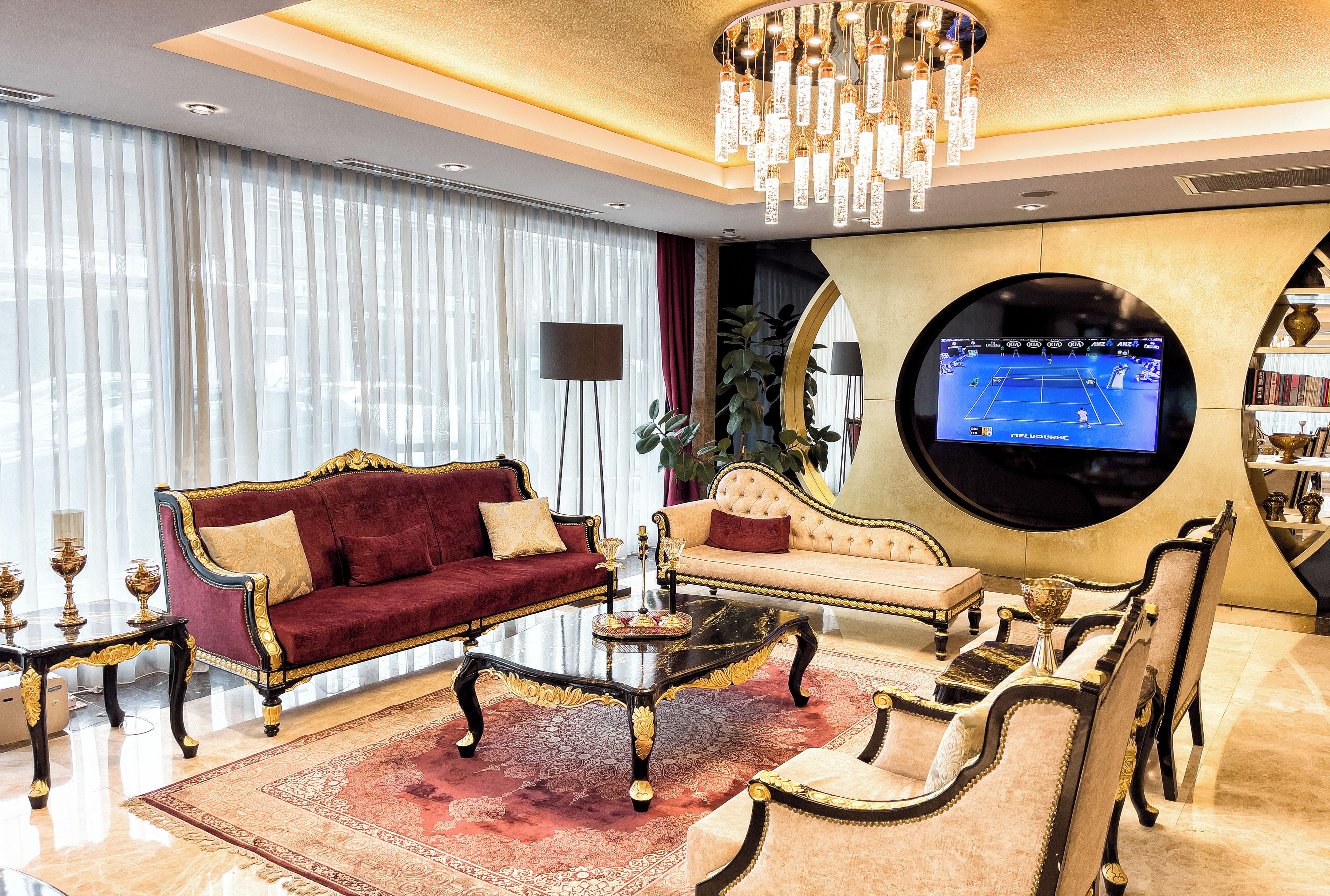 Un salon luxueux avec un canapé rouge, une table basse noire et un écran de télévision rond.