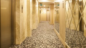 A hotel corridor with a patterned floor, mirrored walls, and doors leading to rooms. - The Conforium Hotel (Istanbul)