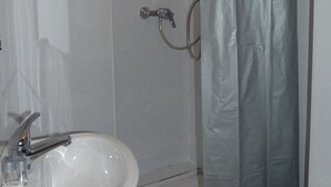 A bathroom with a shower, a sink, and a toilet. - Hôtel du Jura (Paris)
