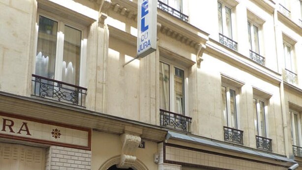 A hotel facade with a prominent sign, a tiled entrance, and a balcony. - Hôtel du Jura (Paris)