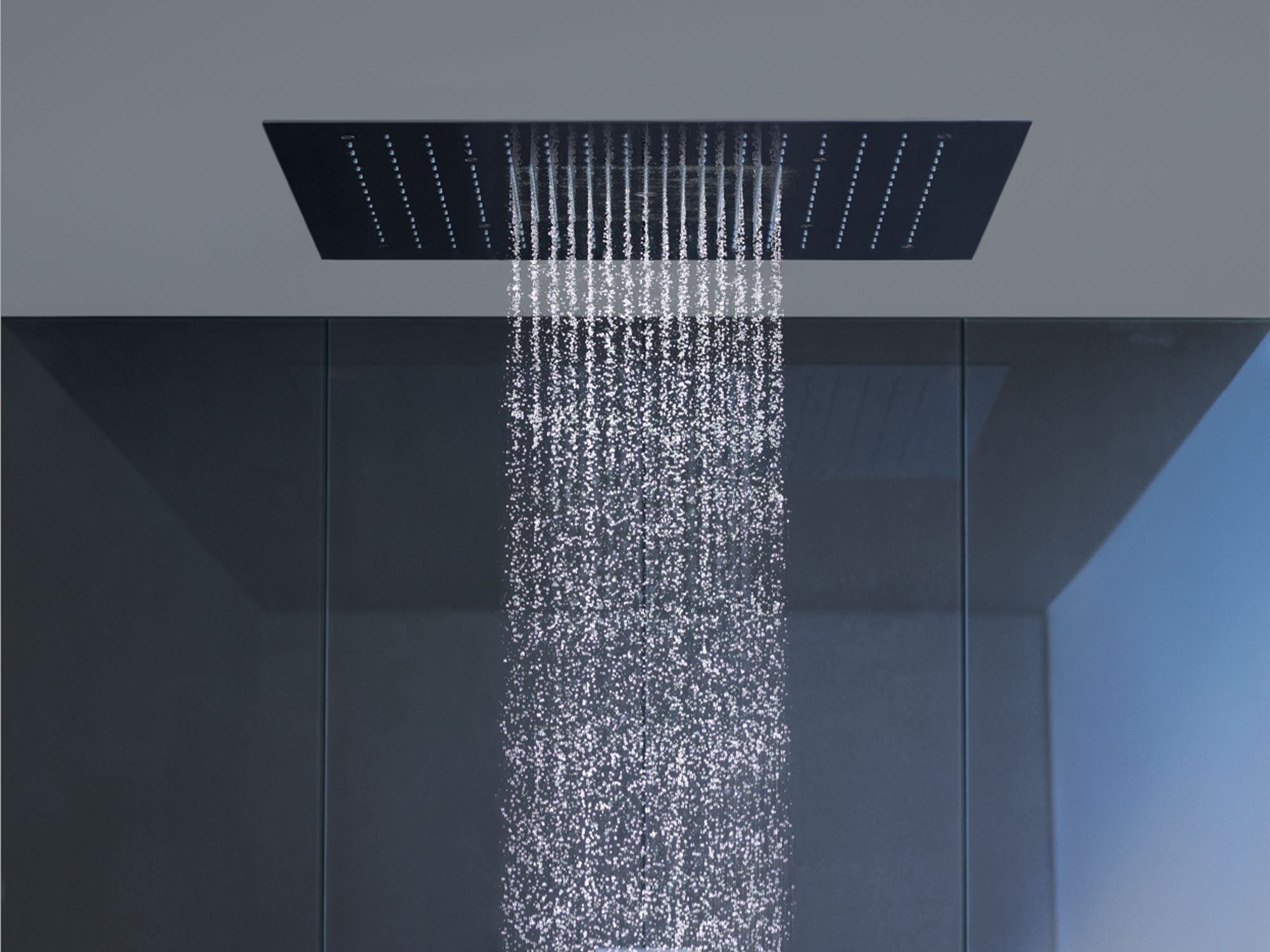 Una ducha moderna con un panel cuadrado de color oscuro y un chorro de agua vertical.