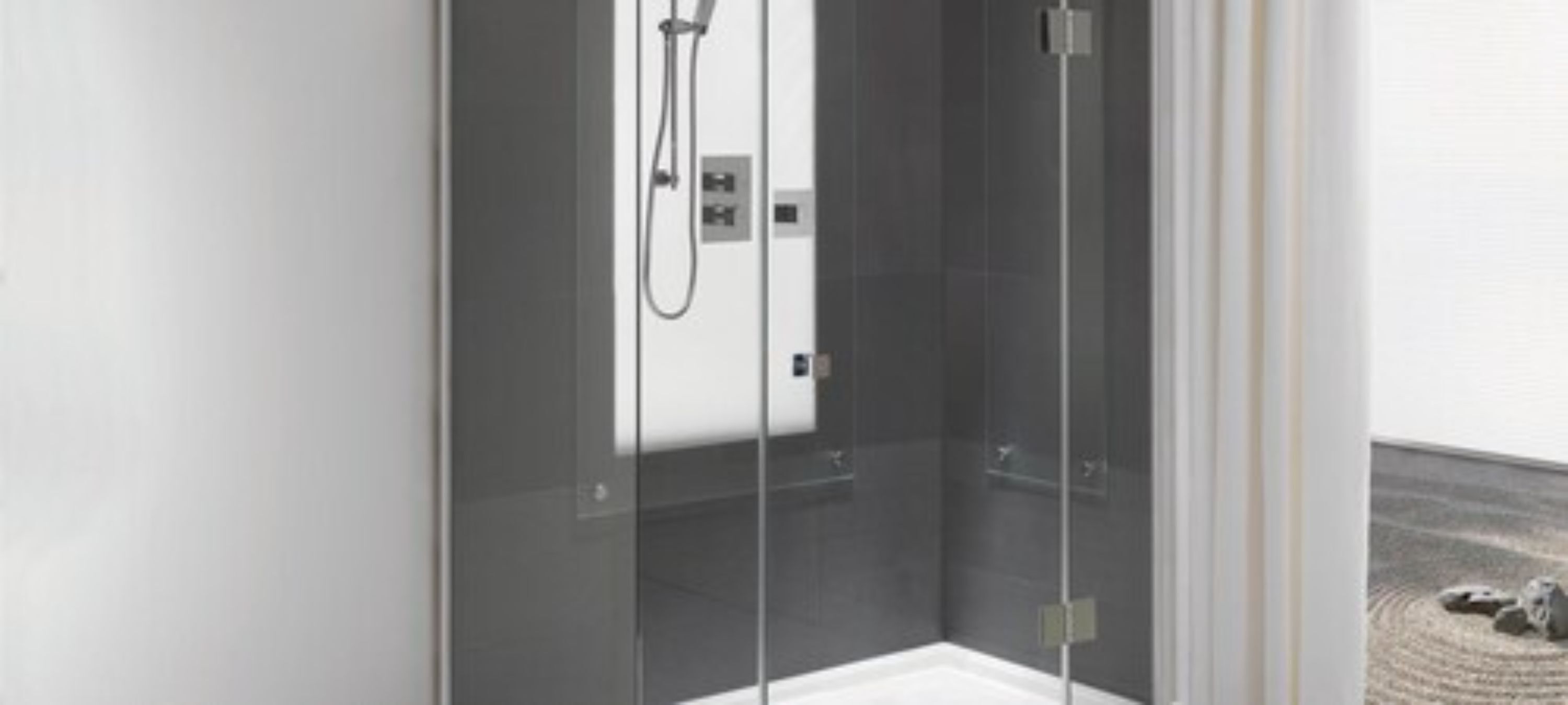 Een moderne douchecabine met een glazen deur, een handdouche en een bedieningspaneel.