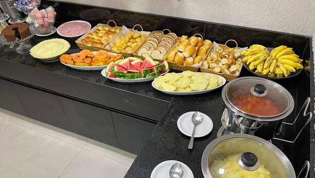 Un bufé con diferentes opciones de comida, incluyendo pan, frutas y un recipiente con alimentos calientes.
