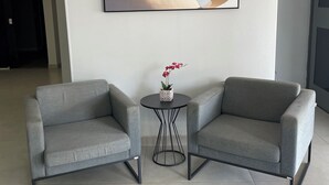 Una habitación moderna con dos sofás grises, una mesita redonda con una planta en maceta y un cuadro abstracto grande en la pared.