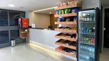 A hotel reception area with a counter, a vending machine, and a trash bin.