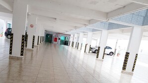 A spacious indoor area with a tiled floor and white pillars, featuring a no-smoking sign and a glass door entrance. - Hotel Flor de Minas (Uberaba)