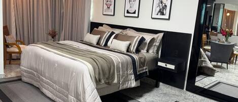 A modern bedroom with a bed, bedside tables, a mirror, and framed pictures on the wall.