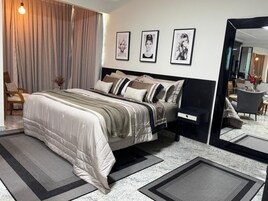 Un dormitorio moderno con una cama, mesitas de noche, un espejo y cuadros en la pared.
