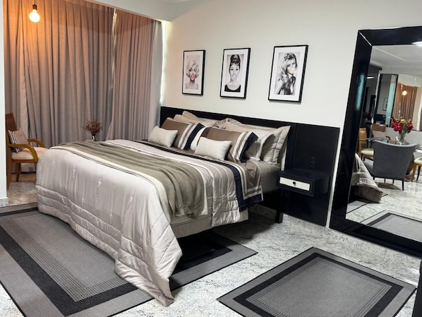 Un dormitorio moderno con una cama, mesitas de noche, un espejo y cuadros en la pared.