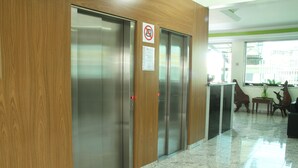 A modern elevator with a wooden panel design, a no-smoking sign, and a note on the wall. - Hotel Flor de Minas (Uberaba)