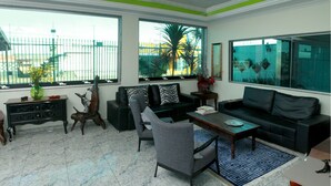 A modern living room with a sofa, armchairs, a coffee table, and a decorative wooden cabinet. - Hotel Flor de Minas (Uberaba)