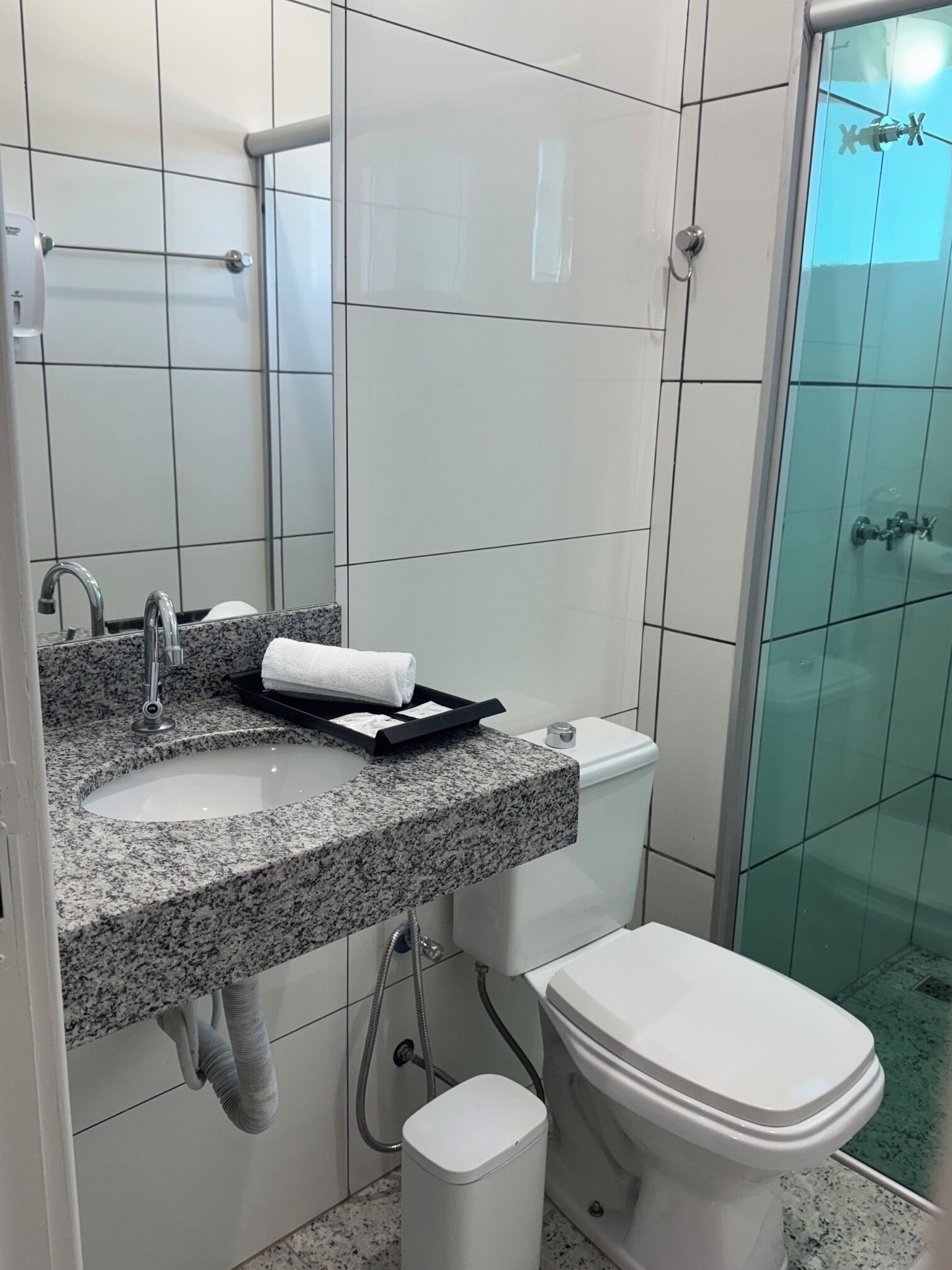 Un baño con lavamanos de encimera de granito, inodoro y cabina de ducha con mampara de vidrio.