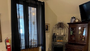 A living room with a leather sofa, a small round table, a wooden cabinet, and a television. - Hall House Hotel (Dahlonega)