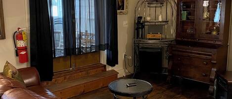 Ein Wohnzimmer mit Ledersofa, einem kleinen runden Tisch, einem Holzschrank und einem Fernseher.