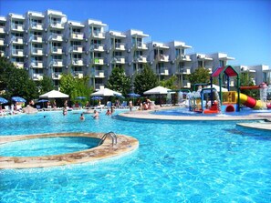 Zona de piscina con tobogán y sillas de descanso.