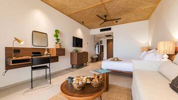A modern hotel room with a wooden ceiling, a desk with a laptop, a bed, and a small dining table with bread baskets.