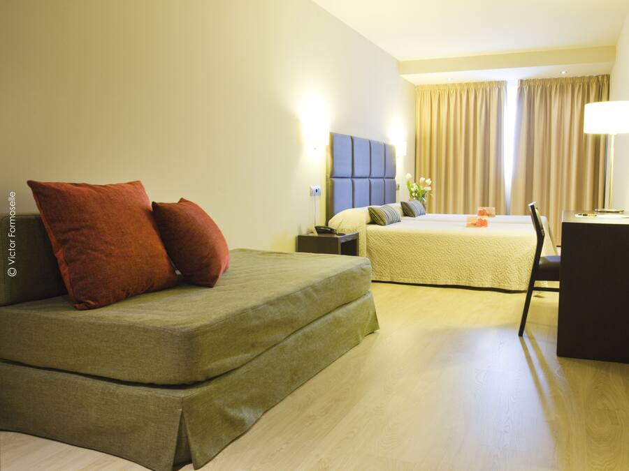 Una habitación de hotel con cama, escritorio y silla.