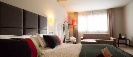 Habitación de hotel con una cama grande, un sofá, un escritorio y una ventana con cortinas.