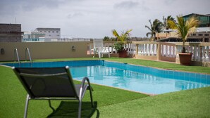 A rooftop pool area with a metal chair, a palm tree, and a potted plant. - Hotel Red Booby (Puerto Ayora)