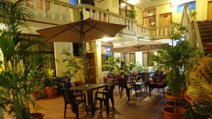 An indoor patio area with multiple tables and chairs, surrounded by potted plants. - Hotel Red Booby (Puerto Ayora)