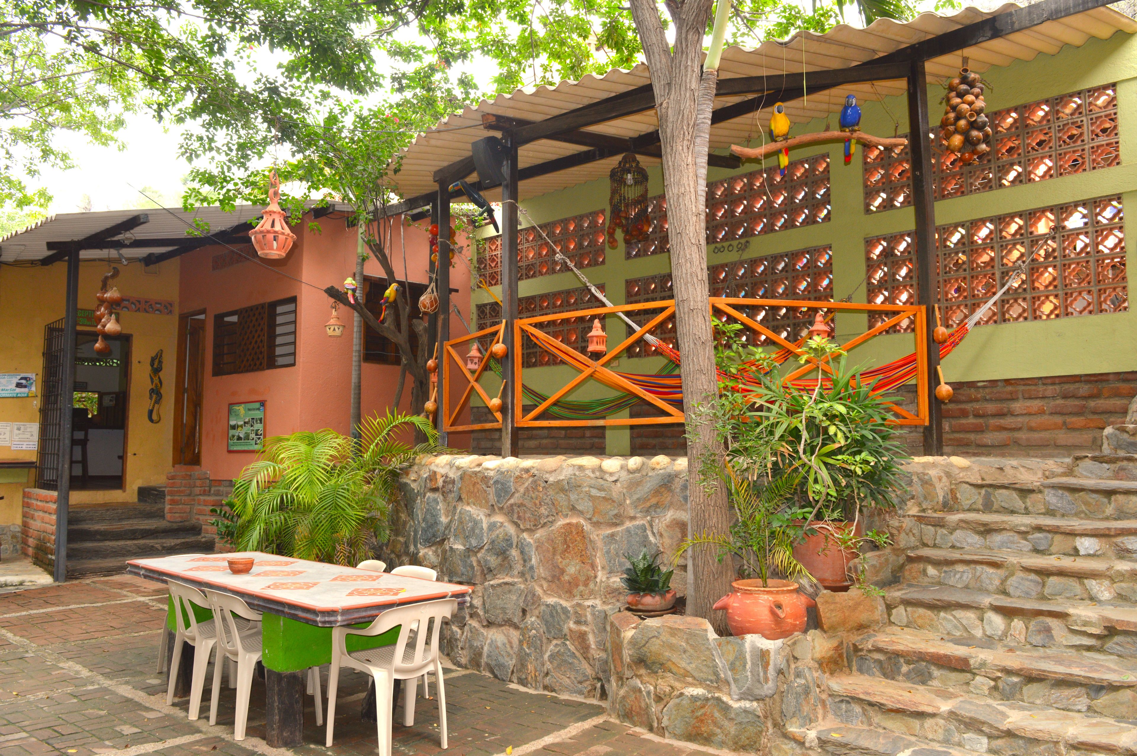 An outdoor patio with a stone wall, a wooden staircase, and a table with chairs.