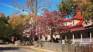Un bâtiment à deux étages, avec un toit rouge et une clôture blanche faite de piquets.
