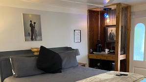 Une chambre à coucher bien rangée, avec un lit, des oreillers, une table de chevet et une commode.