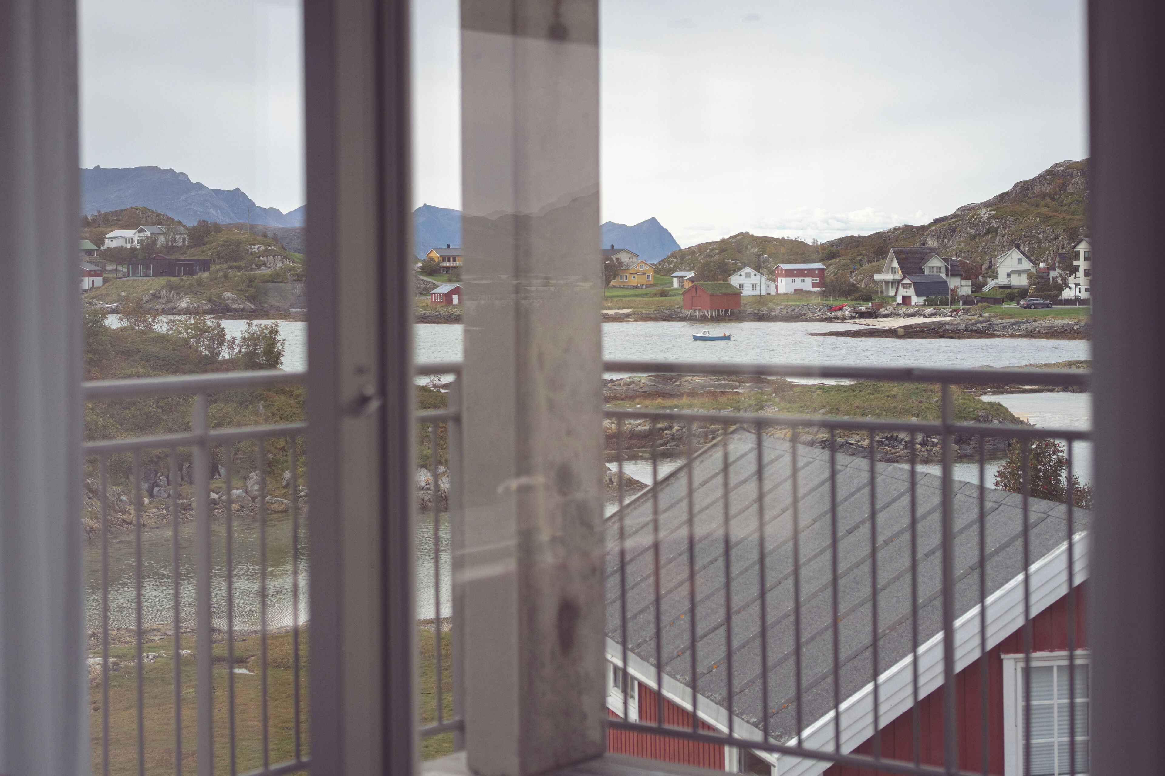 A view from a window overlooking a body of water with houses and mountains in the background.