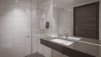 A modern bathroom with a glass-enclosed shower, a large mirror, and a granite countertop.