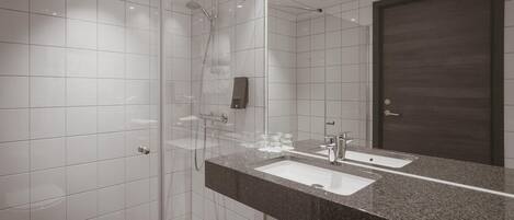A modern bathroom with a glass-enclosed shower, a large mirror, and a granite countertop.