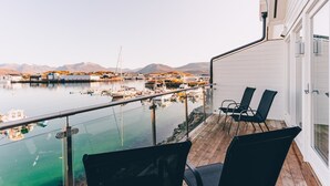 A balcony with two chairs overlooking a marina with boats and mountains in the background. - Sommarøy Arctic Hotel Tromsø (Tromsø)