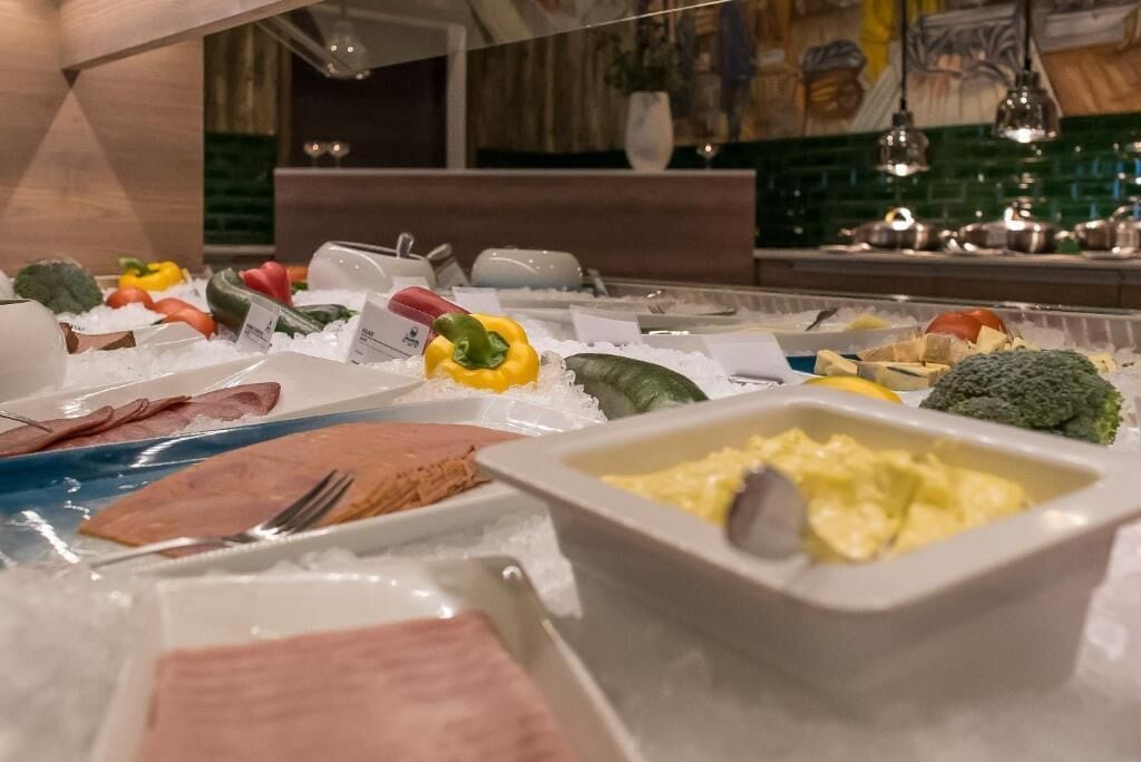 A buffet with various food items like meats, vegetables, and a bowl of scrambled eggs.