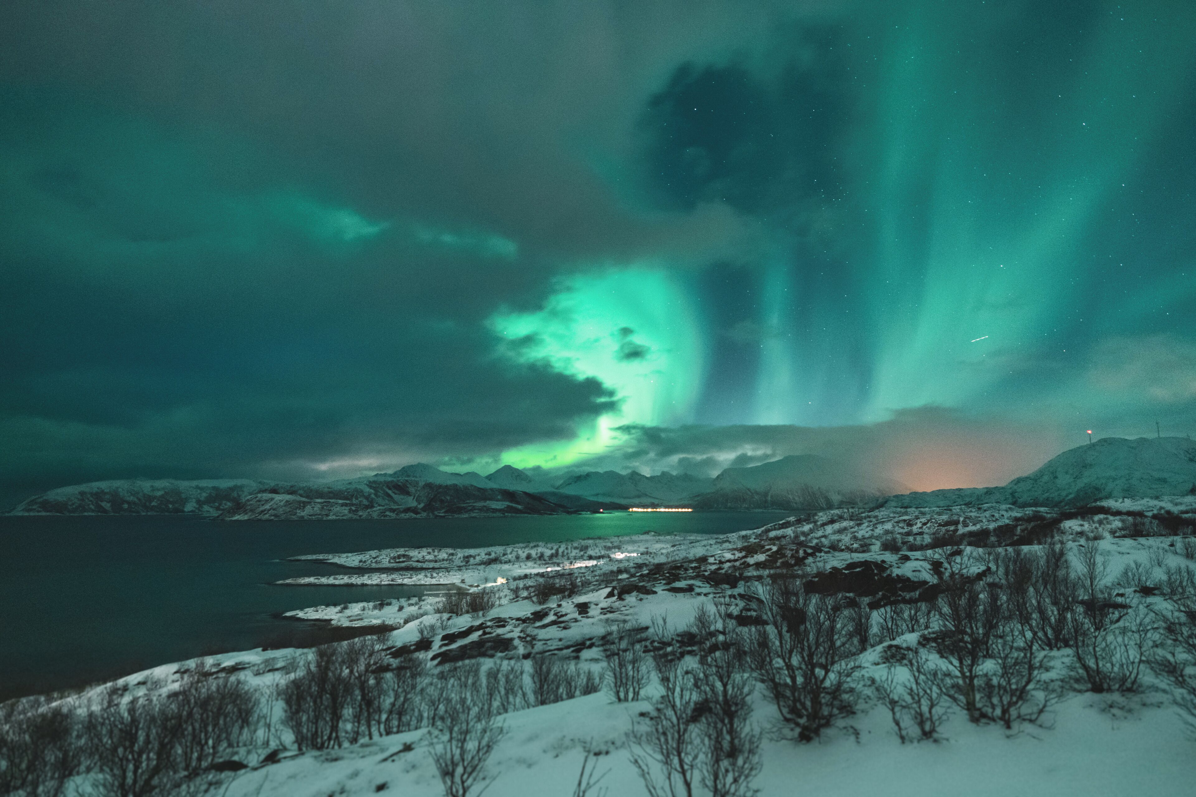 Et snødekt landskab med en sø og bjerge i baggrunden.