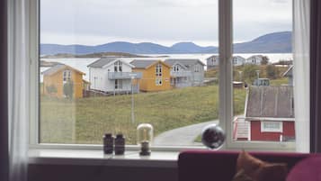 Vista da janela mostrando uma fileira de casas, com um corpo d'água e montanhas ao fundo.