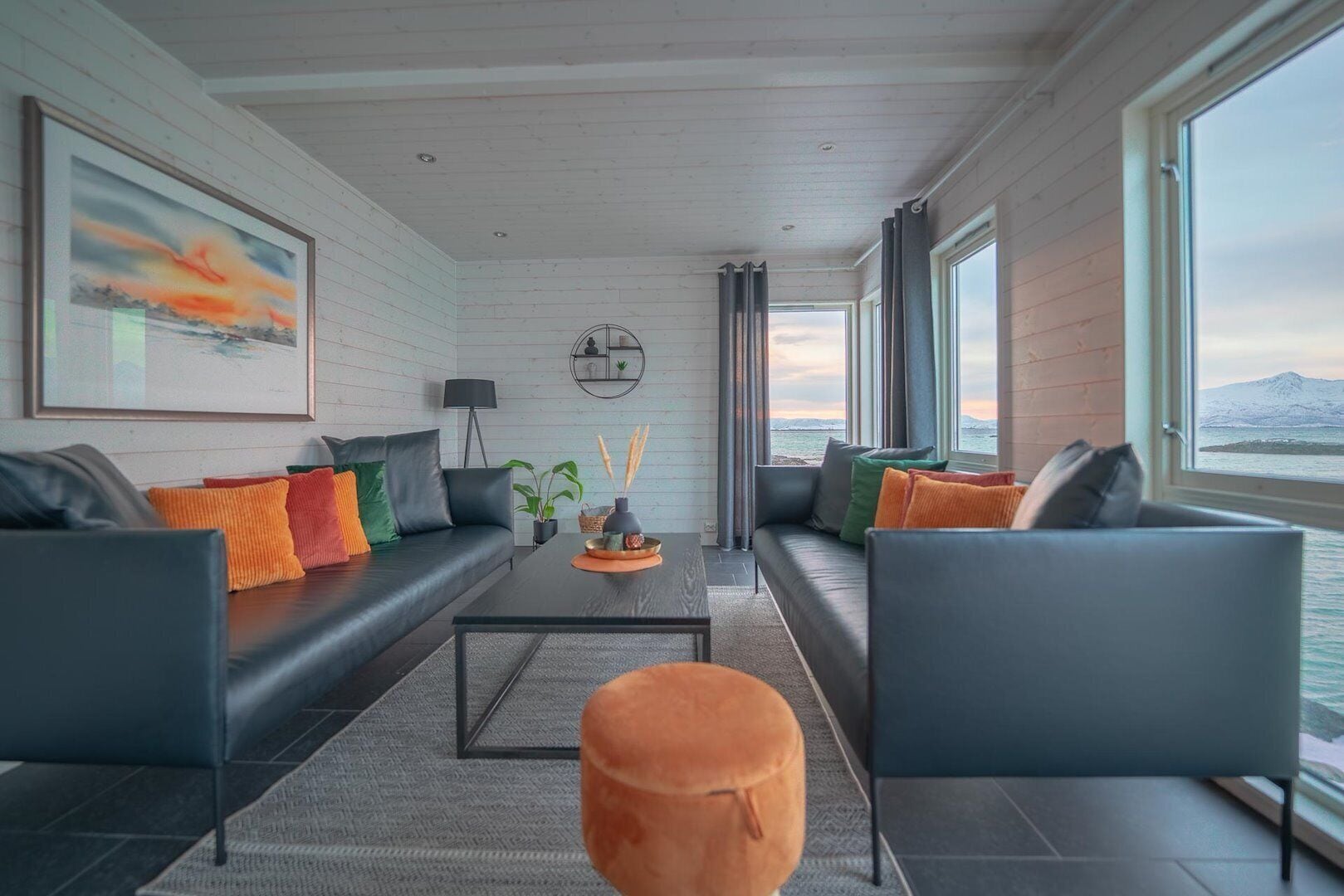 Ein modernes Wohnzimmer mit einer Sofagarnitur, einem Couchtisch und Blick aufs Meer.