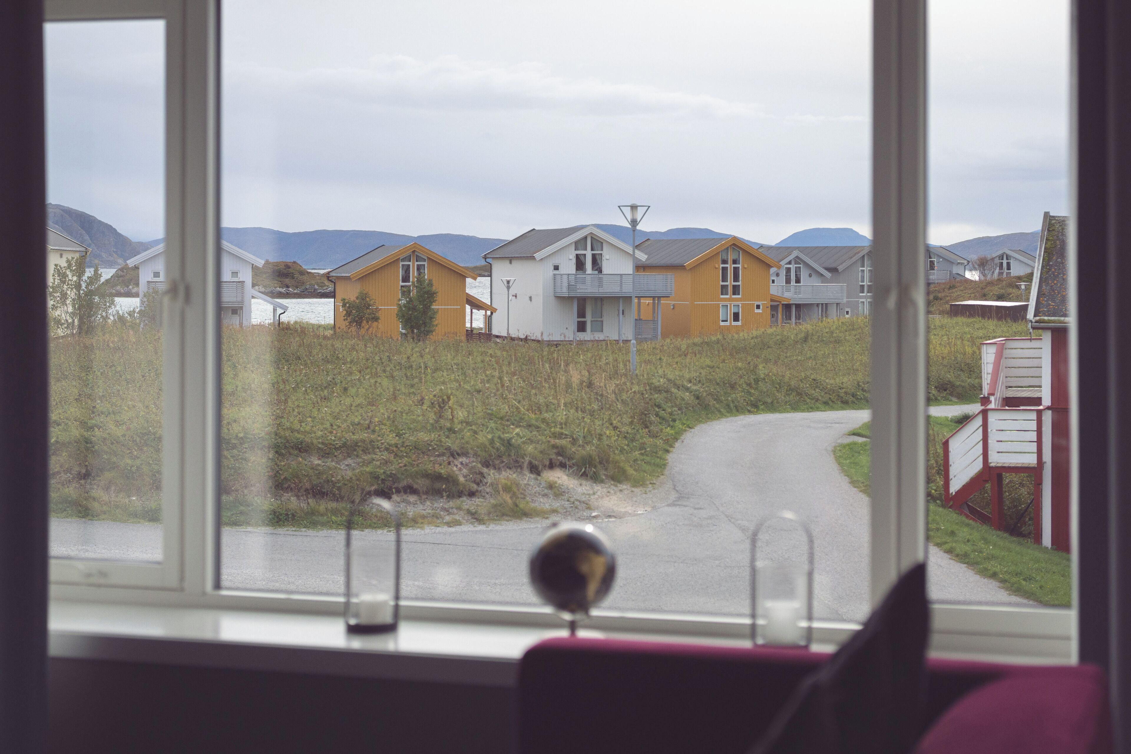 A view from a window of a building with a road leading to houses in the distance.