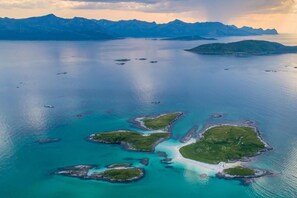 An aerial view of a coastal area with multiple small islands surrounded by clear blue waters.
