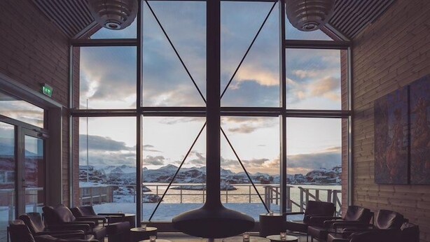 A spacious lounge with large windows offering a view of a snowy landscape and mountains. - Sommarøy Arctic Hotel Tromsø (Tromsø)