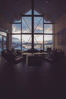 Un amplio salón con ventanas grandes que ofrecen vista a un paisaje nevado y montañas.
