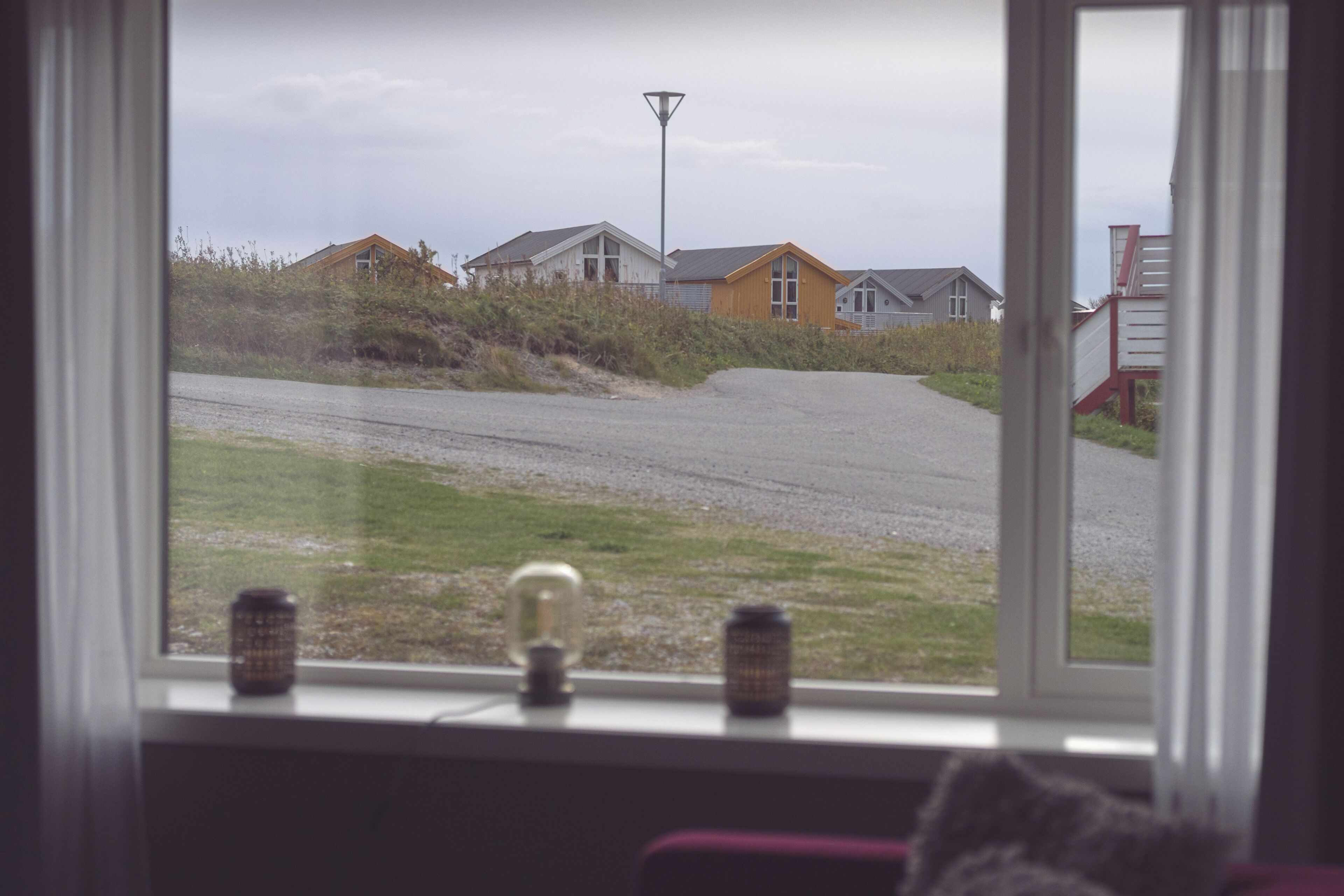 A view from a window overlooking a road with houses and a street lamp.
