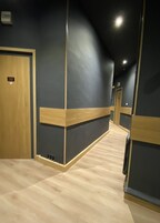 Un pasillo con suelo de madera, paredes oscuras y una puerta con la etiqueta '32'.