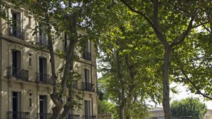 A hotel with balconies, a sign indicating it is a hotel, and a parked car on the street. - Le Strasbourg Hotel (Montpellier)