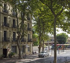 Un hotel con balcones, un cartel que indica que es un hotel y un coche estacionado en la calle.