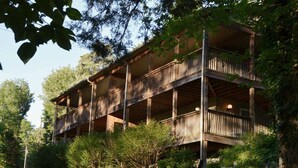 A multi-story wooden building with balconies, surrounded by greenery and trees. - The Retreat at Center Hill Lake (Smithville)