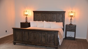 A bedroom with a wooden bed, two bedside tables, and two wall-mounted lamps. - The Retreat at Center Hill Lake (Smithville)