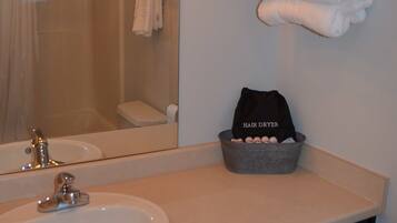 A bathroom with a sink, mirror, towel rack, and a hair dryer basket.