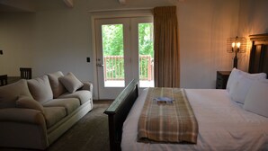 A bedroom with a bed, a sofa, a window with curtains, and a nightstand with a lamp. - The Retreat at Center Hill Lake (Smithville)