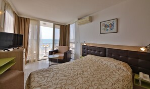 A hotel room with a large bed, a TV, a chair, a small table with drinks, and a balcony with a view. - Hotel Nona All Inclusive (Kranevo)