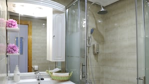 A modern bathroom with a glass-enclosed shower, a white sink, and a mirror above it. - Iberos Jaén (Jaén)